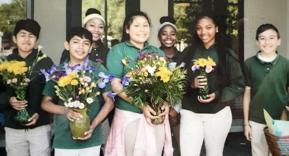 Seven middle schoolers holding flowers in vases